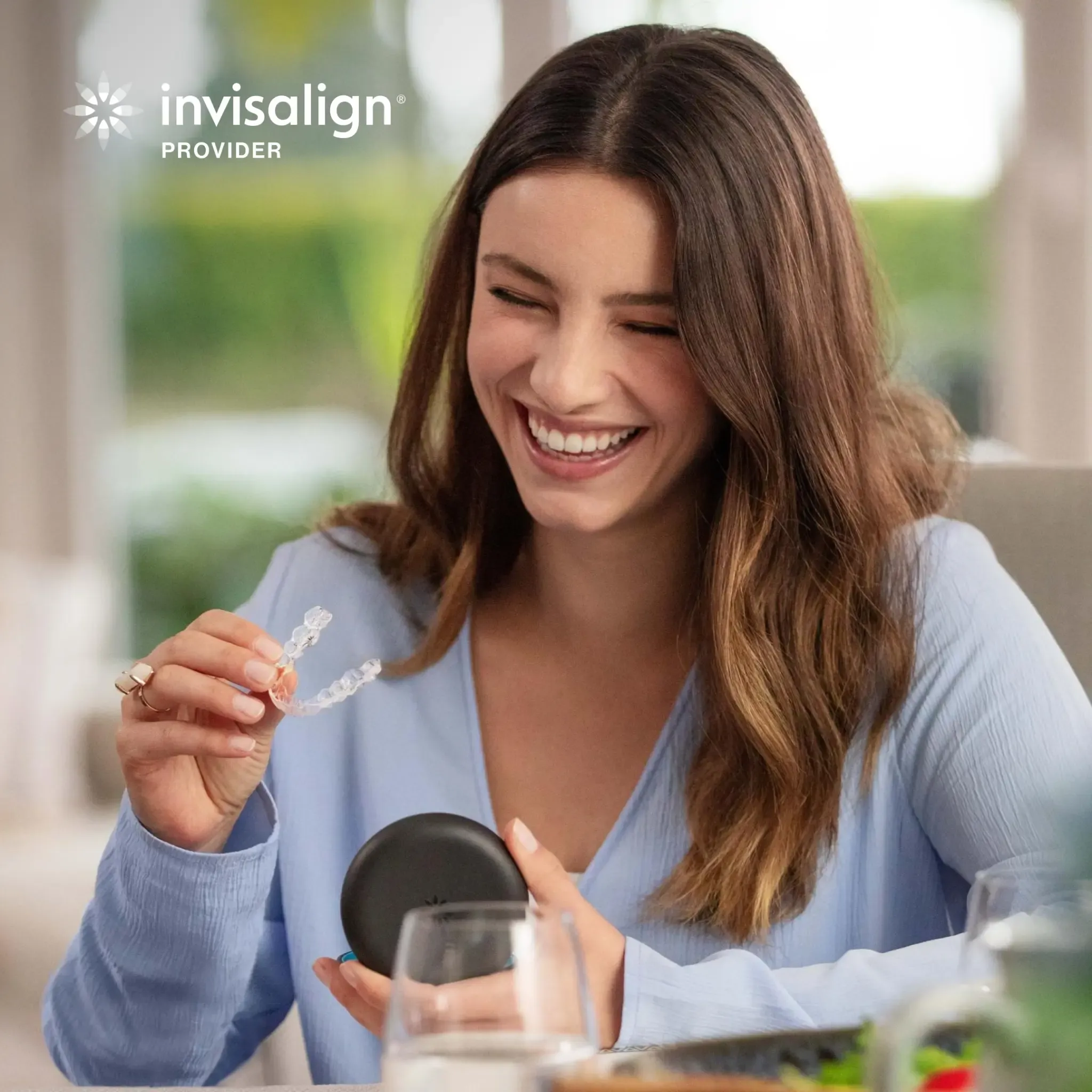 A woman holding an Invisalign clear aligner