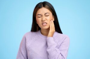 A woman suffering from toothache holds her left check with her left hand.