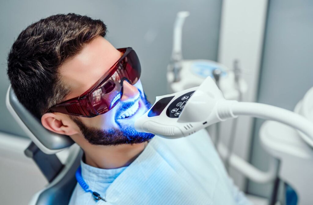 A man with a beard undergoing a teeth whitening procedure that uses ultraviolet light.