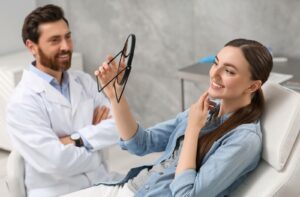 Young woman looking at her new dental implants in mirror indoors