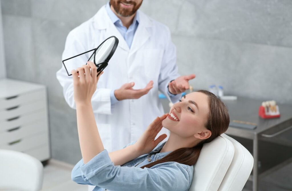 A patient looking at her new dental implants in the mirror at a dental clinic.