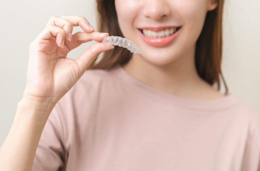 A woman holding up an Invisalign tray.