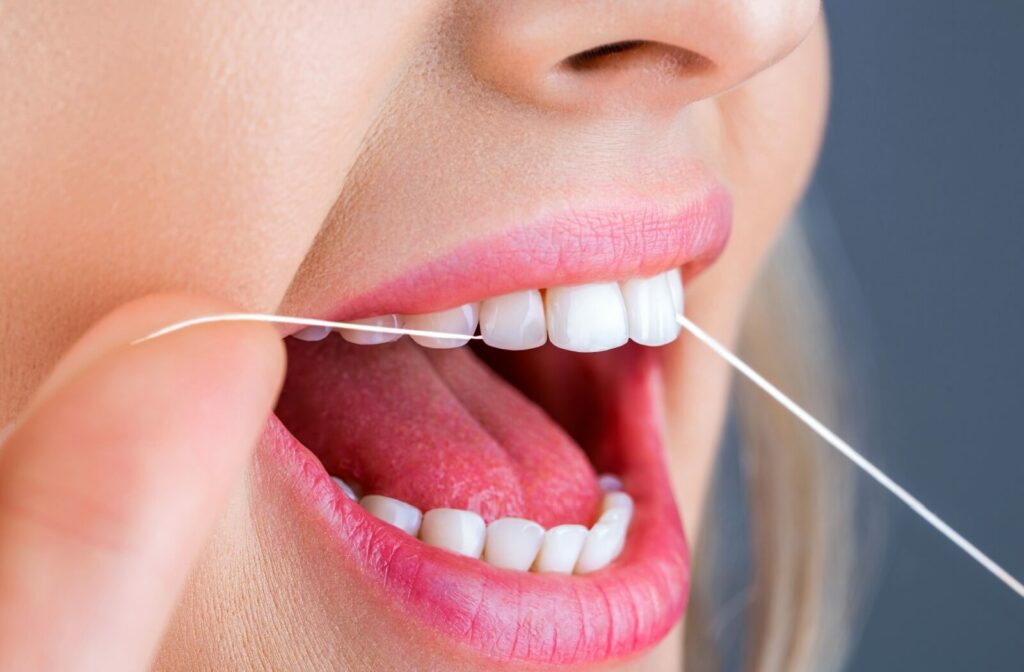 A closeup of a woman flossing her teeth