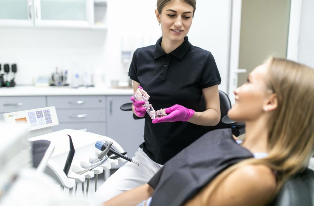 Dental professional showing patient a model of dental implants during consultation.