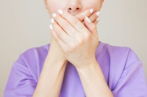 Someone covers their mouth for fear that they have bad breath.