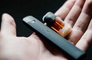 Up close view of disposable vape and cartridge in a hand someone who is vaping