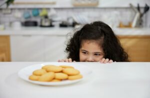 A child looks at a plate of cookies, wondering how long they have to wait after being at the dentist before they can eat.