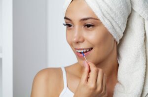 Someone uses an interdental brush instead of floss string, but still effectively cleans their mouth.