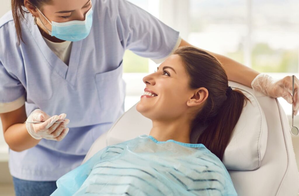 A person smiles brightly during their routine dental exam and cleaning.