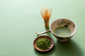Does Matcha Stain Teeth__hero 1 | Belman Dental Centre Matcha tea with a bamboo whisk, spoon, and powdered green tea on a wooden plate.